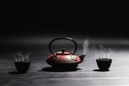 Teapot with two steaming mugs of tea.